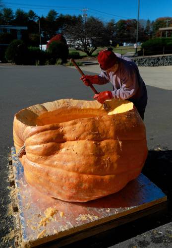 Florence resident Dave Rothstein hallows out a giant pumpkin at Adhesive Applications, where the pumpkin was weighed, Friday afternoon in Easthampton. Rothstein hopes to paddle the pumpkin down the Connecticut River in a world record attempt.