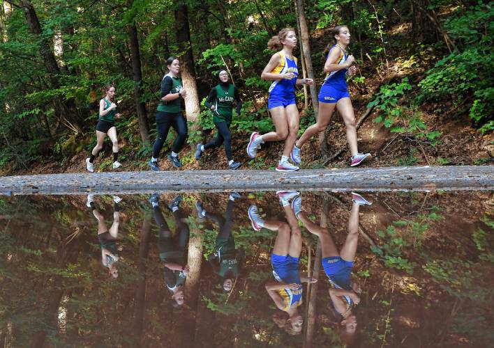 Reflected through a puddle, runners move through the course at Highland Park in Greenfield on Tuesday afternoon.