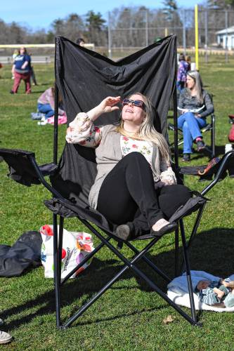 Melissa Osborne of Northfield gets comfortable in her oversized chair while watching the eclipse at a viewing event at Pioneer Valley Regional School on Monday.
