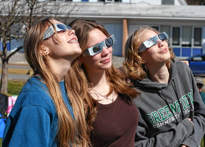 Friends Greta Lewis, Maddie Keefe and Mystic Glenn, all 14 of Northfield, gaze at the sun during an eclipse-viewing event at Pioneer Valley Regional School on Monday.