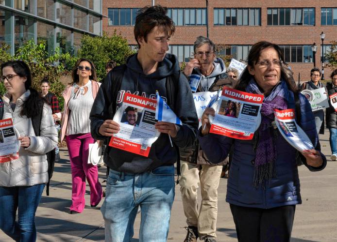 Iris Berkman, at right, walks with her son, Nadav Berkman, while holding a plate with a picture of one of her relatives during an event sponsored by UMass Hillel called “Bring Them Home.” Participants carried plates with flyers that were attached. Each flyer had a picture of one of the 240 hostages kidnapped from Israel by Hamas. Each plate was than taped to tables in a symbolic ritual of Shabbat honoring the hostages.