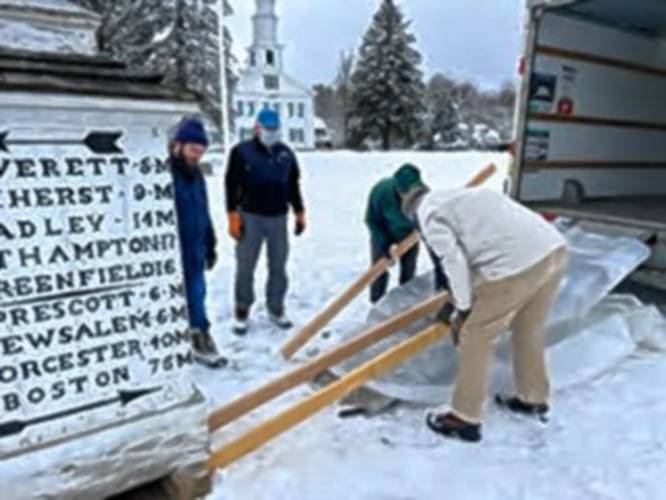 The historic guideboard on the Shutesbury town common is loaded into a truck for a trip to a Williamstown conservator, where it will be restored.