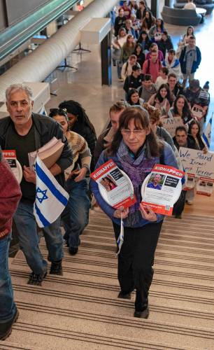 Iris Berkman walks up the steps with others at UMass during an event sponsored by UMass Hillel called “Bring Them Home.” Berkman holds a plate with a photo of one of her relatives. Participants carried plates with flyers that were attached. Each flyer had a picture of one of the 240 hostages kidnapped from Israel by Hamas. Each plate was then taped to tables in a symbolic ritual of Shabbat honoring the hostages.