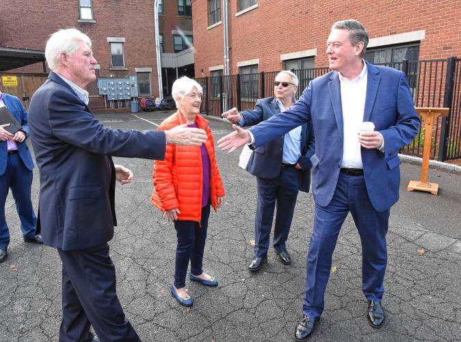 Robert “Butch” Hawkins, left, chair of the Greenfield Housing Authority, greets Massachusetts Housing Secretary Edward Augustus behind the Winslow building with Greenfield Mayor Roxann Wedegartner and Thomas Guerino, executive director of the Greenfield Housing Authority.