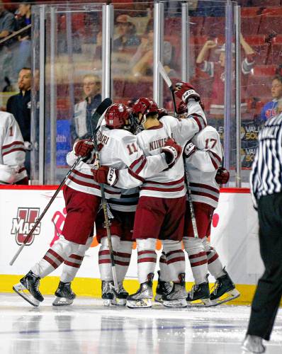 UMass players celebrate a third period goal by Michael Cameron (27) against AIC on Saturday night at the Mullins Center in Amherst.