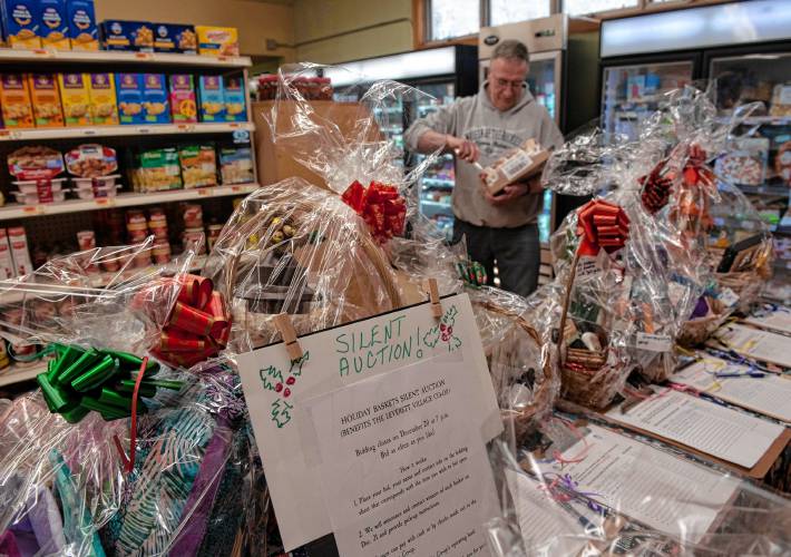 Roger Zimmerman, a volunteer a the Leverett Village Co-Op stocks shelves. In front of him are baskets which are part of a silent auction fundraiser for the Co-Op.