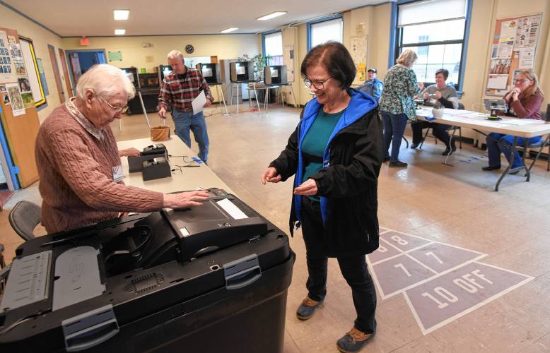 Phylis Dacey helps Cyndie Ouimette cast her vote in Conway Town Hall on Tuesday.