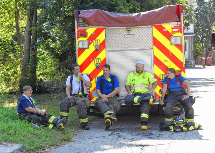 Firefighters rest in the shade after a three-alarm house fire was under control at 92 Fern St. in Athol on a hot Thursday morning.
